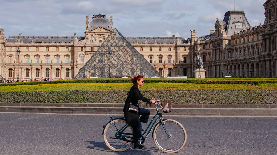 Kvinna som cyklar vid Louvren i Paris.