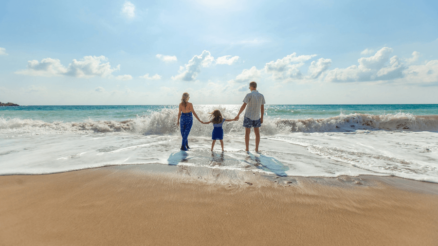 Barnfamilj på en sandstrand som åkt på solresor med all inclusive.